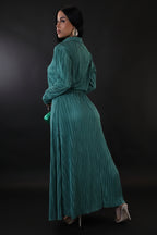 Woman wearing a long teal dress against a plain background