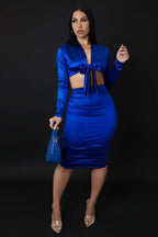 Woman wearing a blue outfit with a matching handbag on a plain background