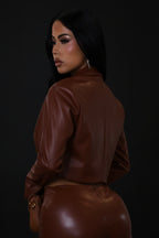 Person wearing a brown leather outfit against a plain background